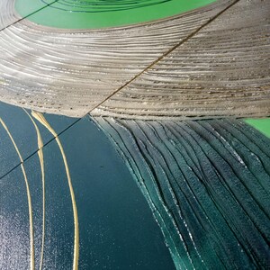 The image is a close-up view of a textured surface with a mix of green, brown, and blue colors. The surface appears to be a combination of different materials or textures, such as wood, metal, and fabric. The colors are vibrant and varied, creating a visually interesting and dynamic composition.