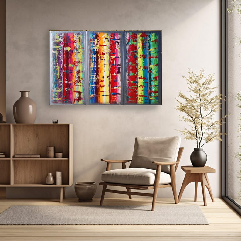 a modern living room with a large, colorful abstract painting hanging on the wall above a wooden chair. The room has a minimalist and clean design, with a wooden floor and a small table with a vase of flowers.