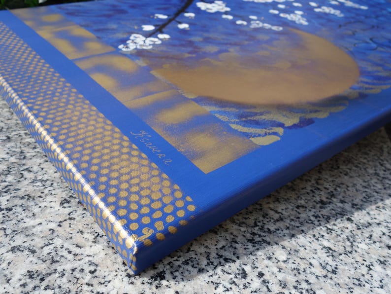 The image is a close-up of a blue and gold canvas with a floral design, featuring a golden flower and a blue background.