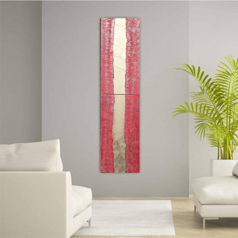 a modern living room with a tall, vertical red and white abstract painting hanging on the wall. The room is furnished with two white sofas and a large potted plant, creating a clean and minimalist aesthetic.