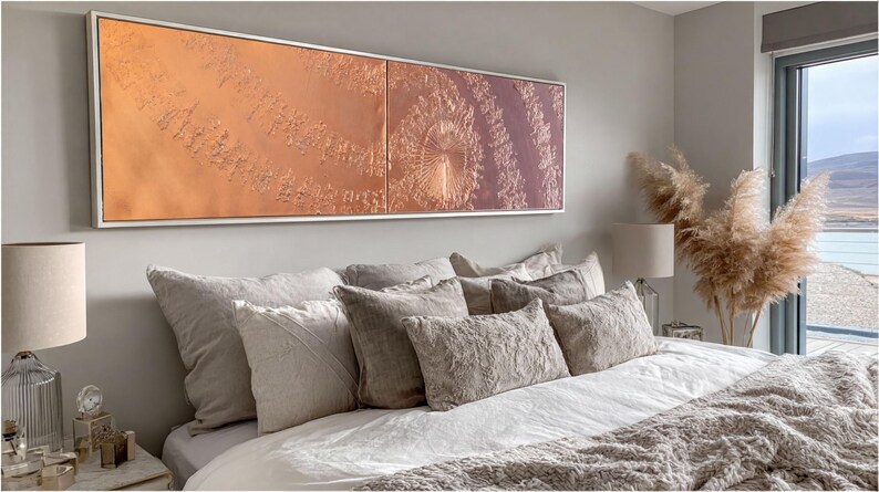 a well-decorated bedroom with a large bed, a framed artwork on the wall, and a large window overlooking a scenic outdoor view.