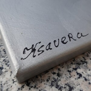 a close-up view of a grey surface with the word "Mavera" written in black cursive handwriting.