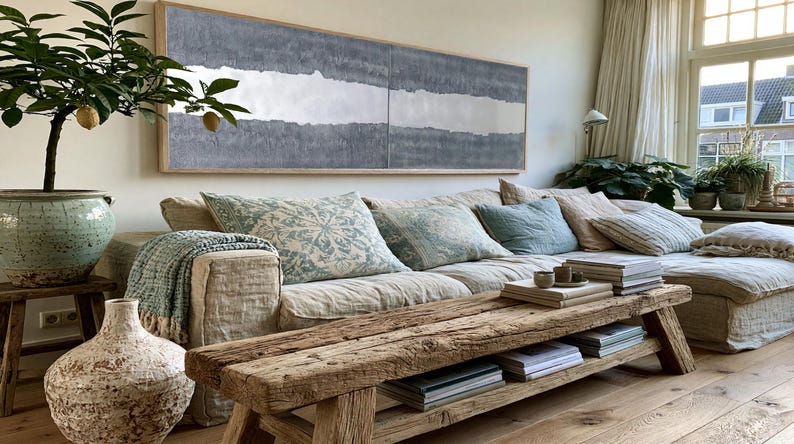 a cozy living room with a large window, a comfortable sofa with patterned pillows, a wooden coffee table, and various decorative elements such as a potted plant, a vase, and a painting on the wall.