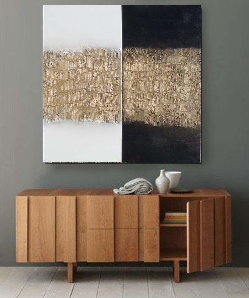 Peut inclure: Tableau abstrait divis&eacute; en deux parties : blanc et noir. Chacune pr&eacute;sente une bande horizontale textur&eacute;e dor&eacute;e. En dessous, un meuble en bois moderne avec une porte partiellement ouverte.