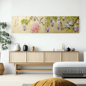 a modern living room with a large, colorful painting of a bird perched on a branch with purple flowers hanging on the wall above a wooden cabinet. The cabinet has a glass front and is adorned with various decorative items such as vases and a teapot. The room also includes a comfortable couch and a potted plant, creating a cozy and inviting atmosphere.