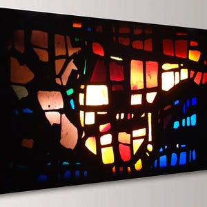 The image is a vibrant, abstract stained glass artwork with a colorful, geometric pattern of shapes and colors.