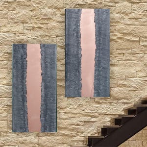 two abstract artworks displayed on a brick wall, with a staircase visible in the background.