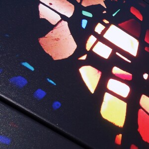 The image is a close-up of a colorful stained glass window, with various shades of red, orange, yellow, and blue creating a vibrant and intricate pattern.