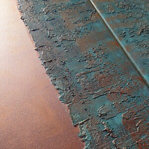 a close-up view of a textured surface with a metallic sheen, featuring a combination of blue and orange colors. The surface appears to be a mix of paint or material with a rough, uneven texture, giving it a somewhat distressed or aged appearance.