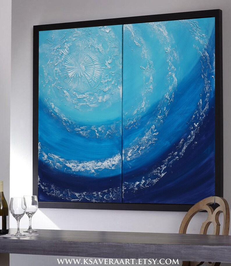 a large, vibrant painting of a blue ocean scene, with swirling patterns and textures that create a sense of movement and depth. The painting is framed and hangs on a wall, with a wooden chair visible in the foreground.