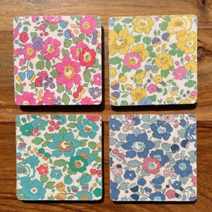 Set regalo di 4 sottobicchieri in legno Liberty in tessuto modello Betsy in 4 colori con nastro abbinato. Ottimo regalo di Natale. Spedizione il giorno successivo incartati