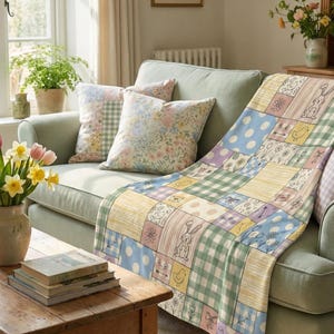 May include: A light green sofa with patterned cushions and a patchwork quilt in a living room setting. The quilt has pastel squares with Easter motifs. A wooden table holds books and a vase of tulips, creating a spring atmosphere.