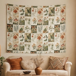 May include: A beige tapestry with a botanical design of flowers, mushrooms, and butterflies hangs above a beige sofa. The tapestry is divided into squares. A wooden coffee table, vase, and pillows complete the cozy living room scene.