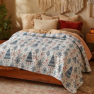 Könnte beinhalten: Ein Bett mit einer weißen Steppdecke mit blauen Weihnachtsbäumen und roten Blumenmustern. Das Bett ist mit beigen und roten Kissen geschmückt, was eine warme und festliche Atmosphäre schafft.