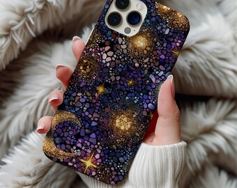 May include: A smartphone case with a celestial design. The case features a mosaic pattern in shades of purple, blue, and gold, with stars and a crescent moon. The case is held in a person's hand, with a soft, textured background.