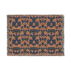 May include: A rectangular woven throw blanket featuring a repeating floral pattern with peach-colored blossoms and dark green leaves set against a deep navy blue background. The edges of the blanket are finished with a decorative fringed border.