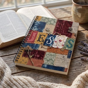 Può includere: Un taccuino a spirale con una copertina in stile patchwork caratterizzata da vari motivi in tessuto nei toni del blu, rosso, verde e marrone chiaro. La parola JESUS è visualizzata in modo prominente con grandi lettere al centro.