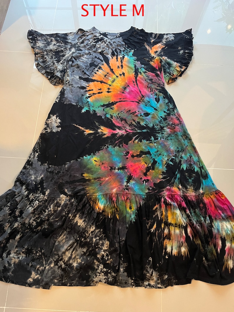 May include: A black maxi dress with a tie-dye pattern in shades of blue, pink, orange, and yellow. The dress has a ruffled neckline and short sleeves with ruffles. The dress has a tiered skirt.