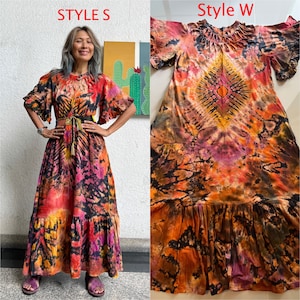 May include: Two tie-dye maxi dresses in different patterns. The dress on the left has a black, orange, and pink pattern with a ruffled hem. The dress on the right has a black, orange, and purple pattern with a ruffled hem. Both dresses have short sleeves.