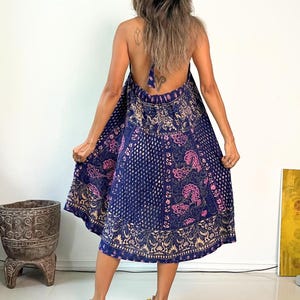 May include: A blue and pink patterned halter dress with a tie back. The dress is made of a soft, flowing fabric and has a relaxed fit.