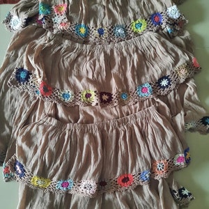 May include: A brown tiered skirt with colorful crocheted trim. Each tier has a different pattern of crocheted flowers.