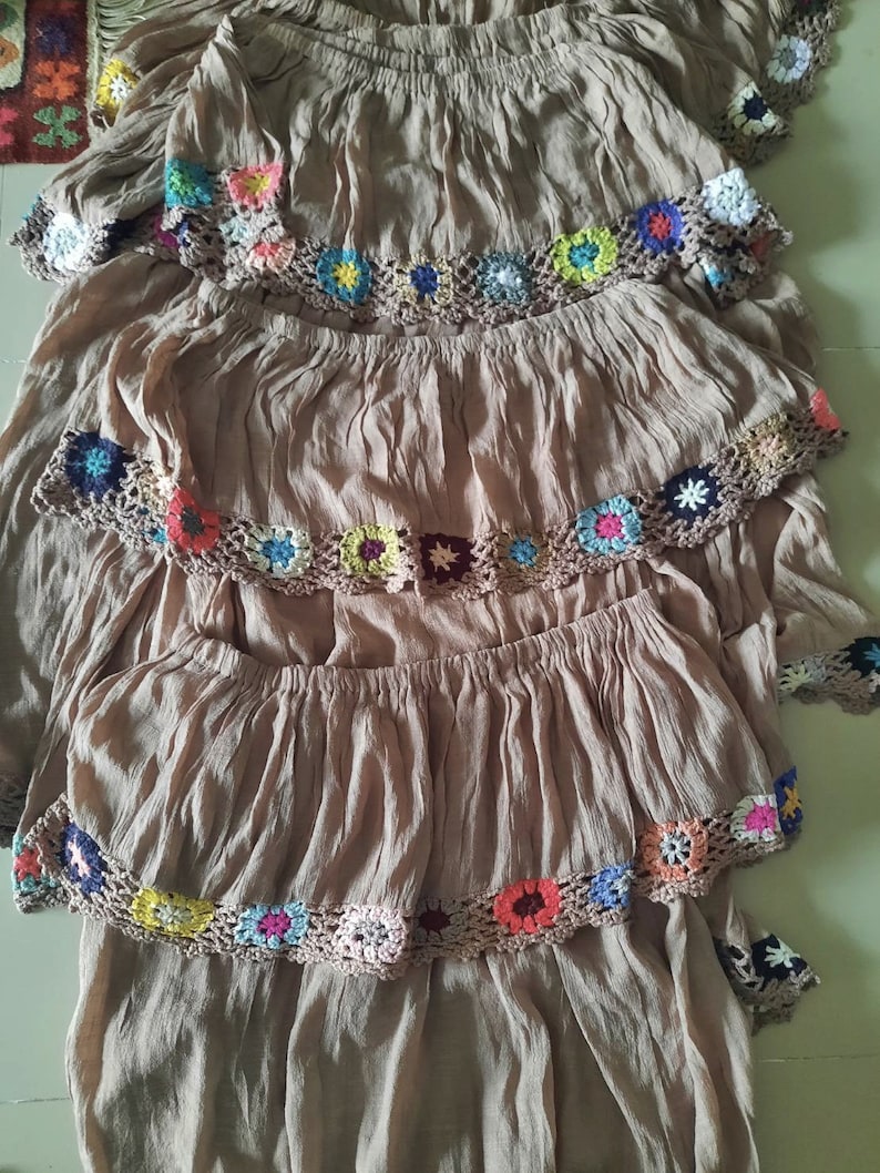 May include: A brown tiered skirt with colorful crocheted trim. Each tier has a different pattern of crocheted flowers.
