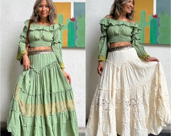 May include: Two women wearing a green and white layered maxi skirt with a green off-the-shoulder crop top. The skirt has a lace trim and the top has a ruffled neckline.