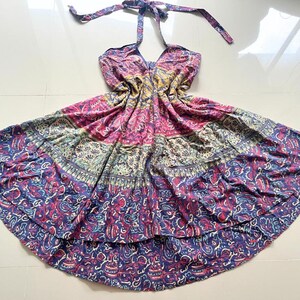 May include: A multi-colored halter dress with a floral print. The dress has a tiered skirt and a loose fit.