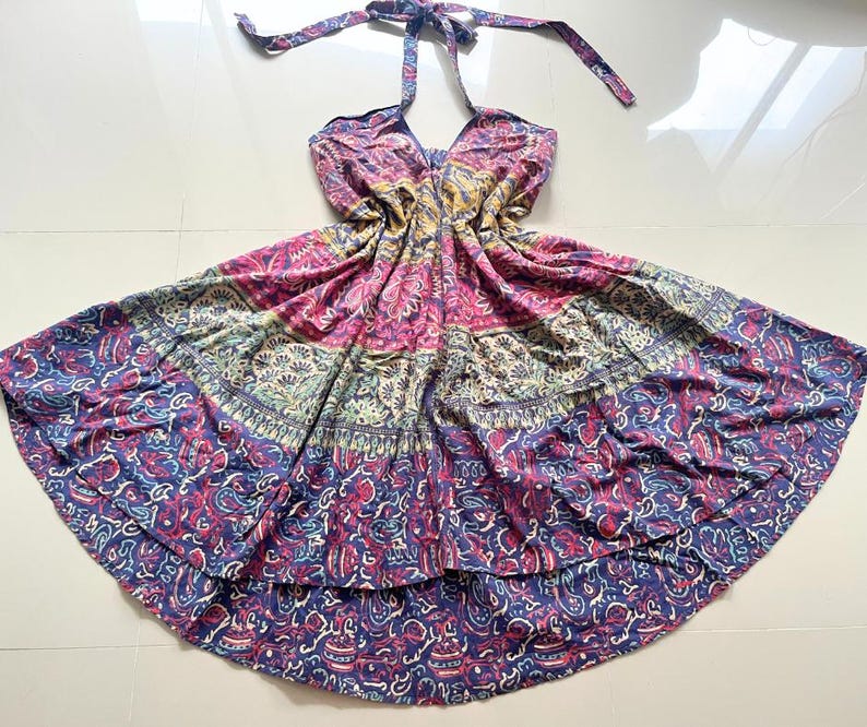 May include: A multi-colored halter dress with a floral print. The dress has a tiered skirt and a loose fit.