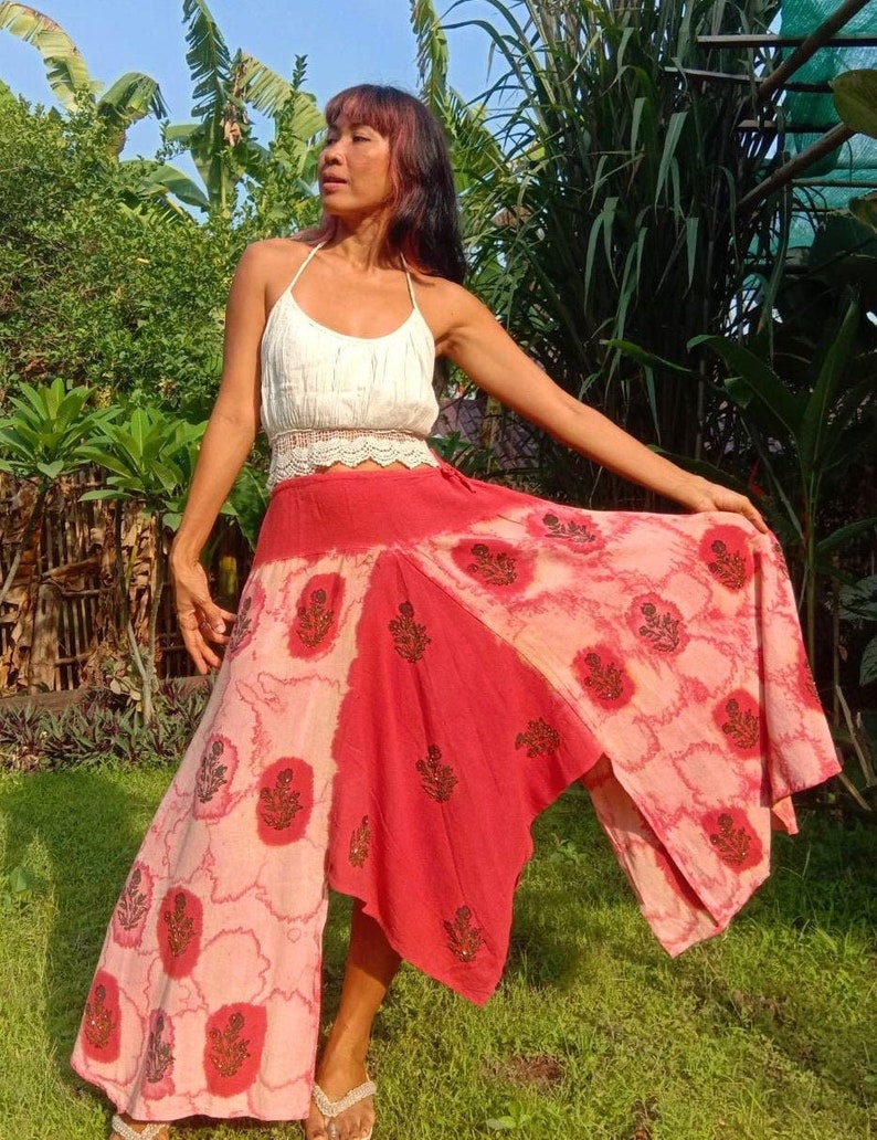 May include: A red and pink tie-dye skirt with a floral print. The skirt is asymmetrical and has a long, flowing design.