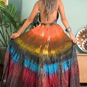 Pode incluir: Um vestido maxi longo de tie-dye com decote halter e um padr&atilde;o degrad&ecirc; colorido em tons de laranja, marrom, azul e vermelho.