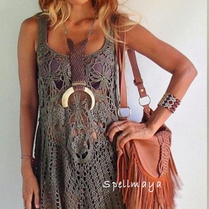 May include: Olive green crochet dress with a fringed bag. The dress has a loose fit and a scalloped hem. The bag is brown leather with a long fringe.