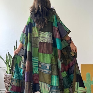 May include: A loose-fitting, long-sleeved patchwork kimono-style robe featuring a variety of green, blue, brown, and purple fabric panels with diverse patterns, including tie-dye, geometric prints, and Om symbols. The garment is labeled JK3.