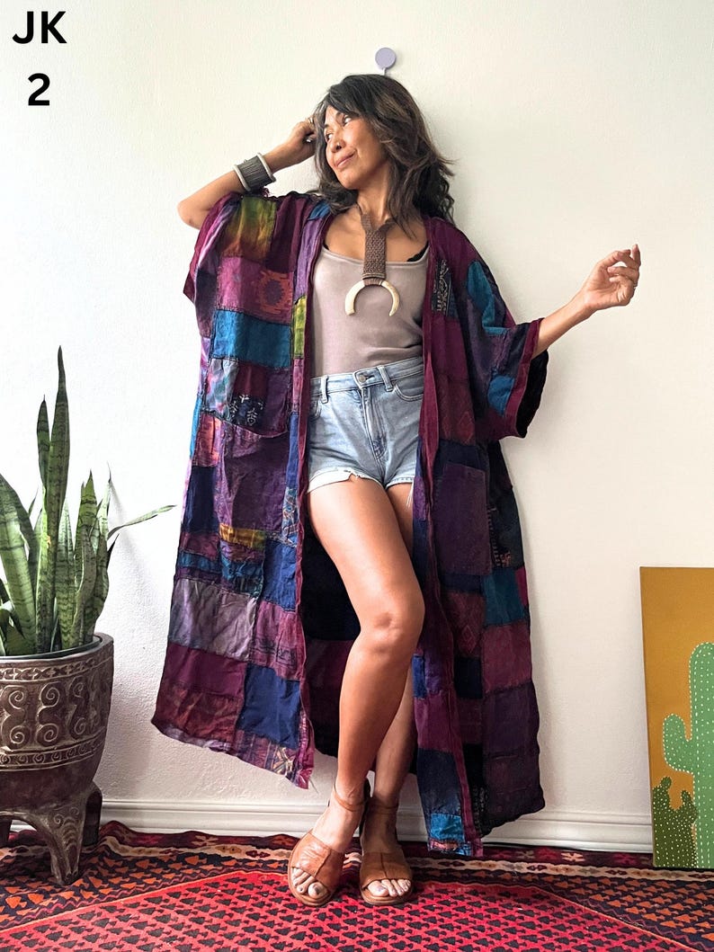 May include: A long, open-front kimono jacket featuring a patchwork design in various shades of purple, blue, and dark red. The garment has wide sleeves and a loose, flowing silhouette. The text JK 2 is visible in the upper left corner of the image.