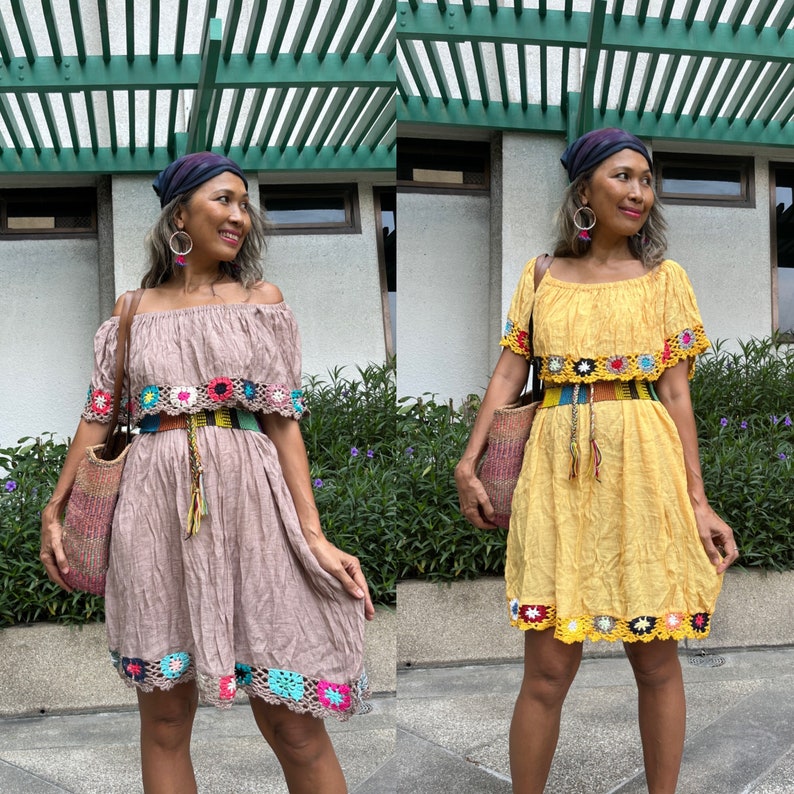 May include: Two women wearing crochet dresses with colorful trim and floral embroidery. The dress on the left is brown and the dress on the right is yellow. Both women are wearing headbands and carrying bags.