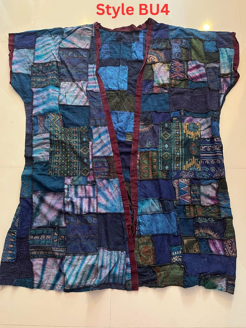 May include: A sleeveless open-front vest featuring a patchwork design in various shades of blue, teal, and purple. The garment displays diverse patterns, including geometric shapes, tie-dye, and script text. It has a dark maroon trim. Style BU4.
