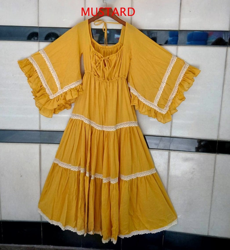 May include: A mustard yellow maxi dress with a scoop neck and bell sleeves. The dress has a lace trim and a tiered skirt.