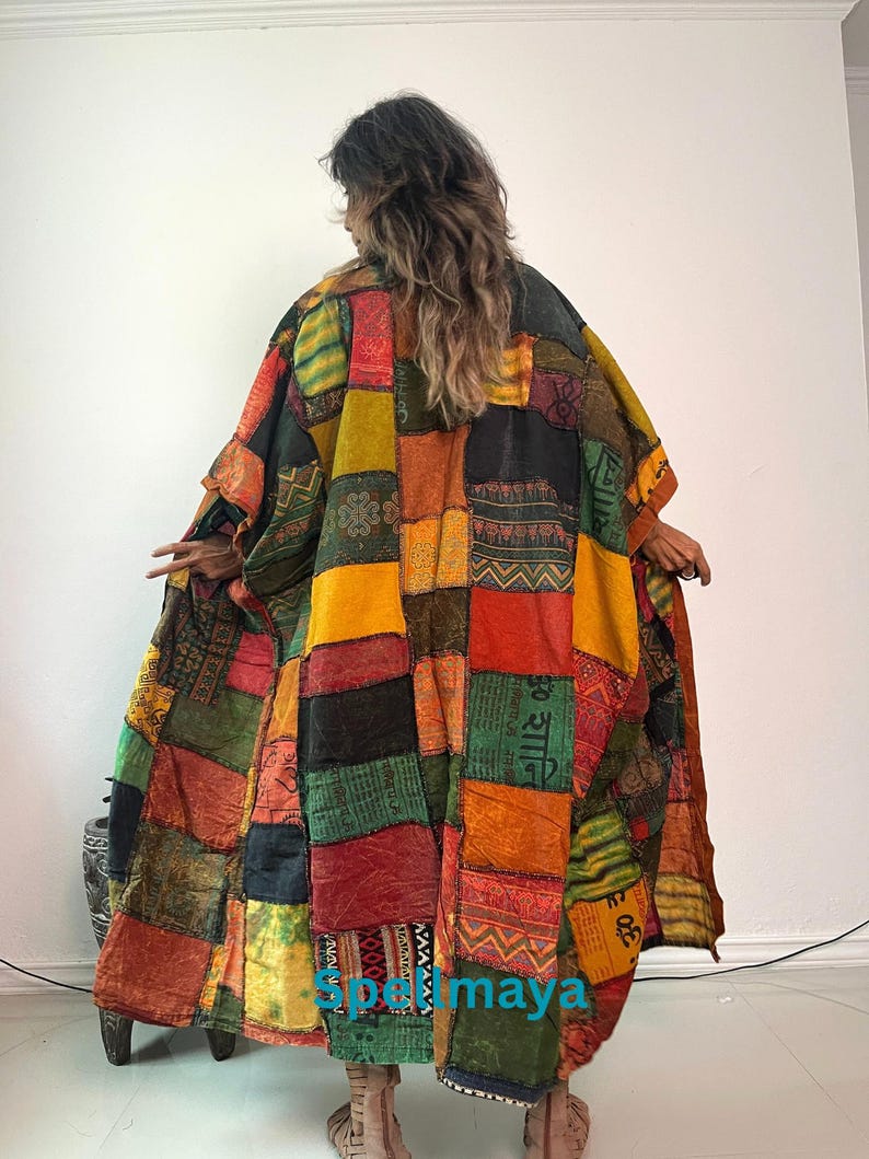 May include: A long, loose-fitting patchwork kimono-style robe featuring a vibrant array of rectangular fabric panels in shades of mustard yellow, deep red, forest green, and black. The garment displays various printed patterns and Sanskrit text.