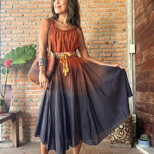May include: A sleeveless, ombre-dyed dress in shades of rust and charcoal. The dress features a fitted bodice and a flowing skirt, cinched at the waist with a decorative belt. The text "Dress D4" is visible in the upper left corner.
