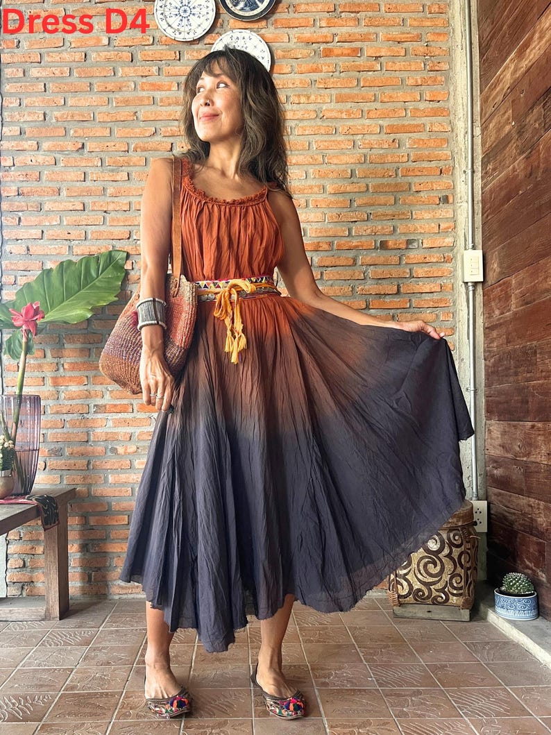May include: A sleeveless, ombre-dyed dress in shades of rust and charcoal. The dress features a fitted bodice and a flowing skirt, cinched at the waist with a decorative belt. The text "Dress D4" is visible in the upper left corner.