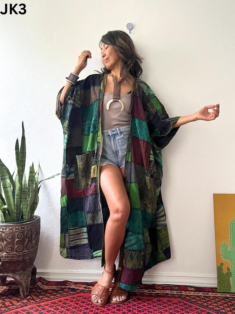 May include: A long, open-front kimono featuring a patchwork design of various green, black, and maroon fabric panels with intricate patterns. The garment has wide sleeves and two front pockets. The text JK3 is visible in the top left corner.
