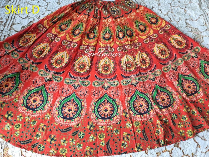Pu&ograve; includere: Una gonna rossa, verde e gialla con un motivo a mandala. La gonna &egrave; in cotone e ha uno stile fluido e boh&eacute;mien.
