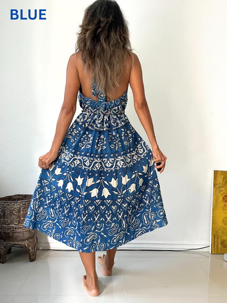 May include: A blue and white floral print maxi dress with a halter neckline and a tie back. The dress has a tiered skirt and a relaxed fit.