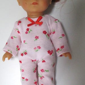 May include: A pink doll pajamas with a red bow and a floral print. The pajamas are made of soft cotton and are perfect for a doll's bedtime.