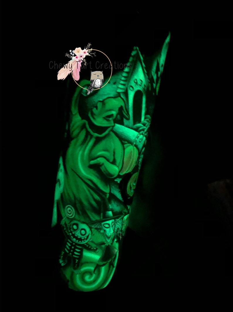 Puede incluir: Un vaso verde que brilla en la oscuridad con un dise&ntilde;o de Jack Skellington de la pel&iacute;cula Pesadilla antes de Navidad. El vaso presenta a Jack Skellington sosteniendo una calabaza con una casa encantada en el fondo.