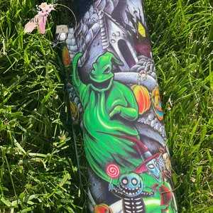 Puede incluir: Un vaso negro y verde con un dise&ntilde;o de tem&aacute;tica de Halloween. El dise&ntilde;o presenta un fantasma verde, un esqueleto y una calabaza. El vaso tiene una tapa negra.