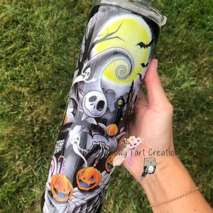 Puede incluir: Un vaso negro y blanco con un dise&ntilde;o de Pesadilla Antes de Navidad. El dise&ntilde;o presenta a Jack Skellington, Sally y otros personajes de la pel&iacute;cula. El vaso est&aacute; decorado con purpurina y tiene una tapa transparente.