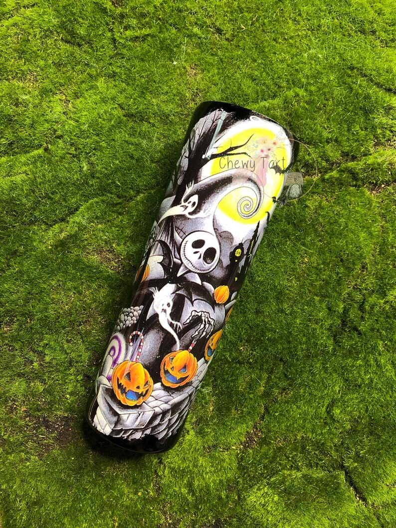 Puede incluir: Un vaso negro y blanco con un dise&ntilde;o de Pesadilla Antes de Navidad. El dise&ntilde;o presenta a Jack Skellington, Sally y otros personajes de la pel&iacute;cula. El vaso tambi&eacute;n tiene una luna amarilla con un dise&ntilde;o en espiral y el texto "Chewy Tart".