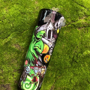 Puede incluir: Un vaso de acero inoxidable negro y verde con un estampado gr&aacute;fico de personajes de Pesadilla antes de Navidad. Los personajes incluyen a Jack Skellington, Sally y Oogie Boogie. El vaso tiene un fondo negro con un dise&ntilde;o de remolino verde.