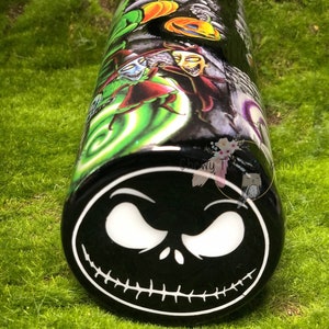 Puede incluir: Un vaso negro y verde con un dise&ntilde;o de Pesadilla Antes de Navidad. El vaso presenta una imagen en blanco y negro de la cara de Jack Skellington en la parte inferior.